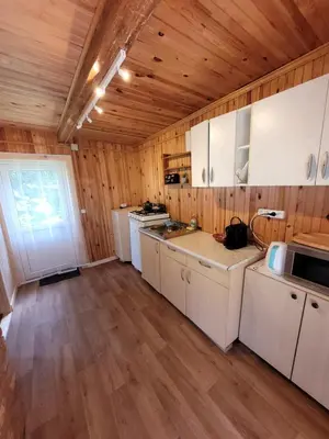 a kitchen with white cabinets and a wooden ceiling at Šeimos namelis nr2-Mindūnų sodyba in Pakopi
