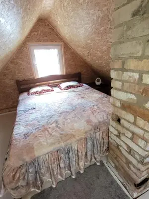 a bedroom with a bed in a brick wall at Šeimos namelis nr2-Mindūnų sodyba in Pakopi