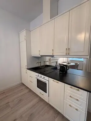 a kitchen with white cabinets and a black counter top at Luxury Apartment Self Check-In in Vilnius