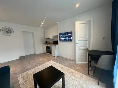 a living room with a table and a kitchen at Next door airport apartmens in Karmėlava