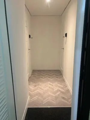 a walk in closet with white walls and a wooden floor at Next door airport apartmens in Karmėlava