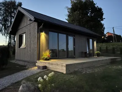 a small cabin with a wooden deck in a yard at Tytų Vila in Tytuvėnai