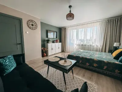 a living room with a couch and a bed and a table at Central Park Apartment in Šiauliai
