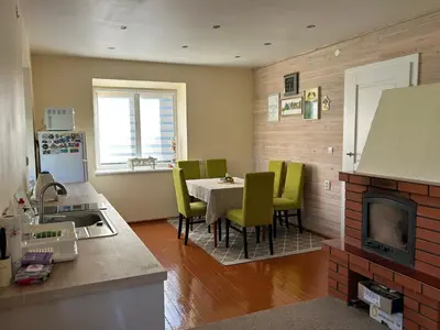 a kitchen with a table and green chairs in a room at Bocmano vila in Meteliai