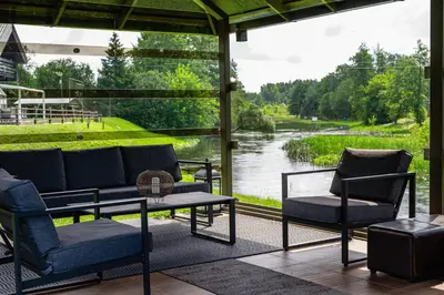 a screened in porch with a view of a river at Romuvos Parkas in Zalioji