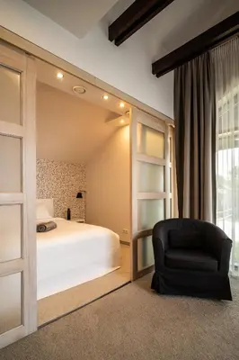 a bedroom with a bed and a black chair at Romuvos Parkas in Zalioji