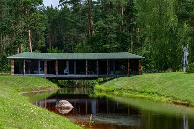 a building on a bridge over a river at Romuvos Parkas in Zalioji