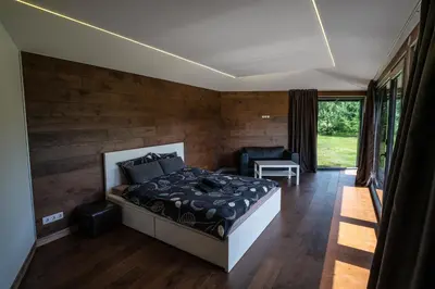 a bedroom with a bed in a room with wooden walls at Romuvos Parkas in Zalioji