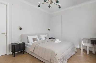a white bedroom with a bed and a chair at SongInn Deco Apartment in Kaunas