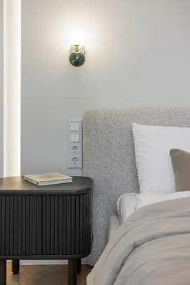 a bed with a side table with a clock on it at SongInn Deco Apartment in Kaunas