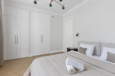 a white bedroom with a large bed with white cabinets at SongInn Deco Apartment in Kaunas