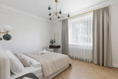 a white bedroom with a bed and a window at SongInn Deco Apartment in Kaunas