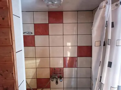 a bathroom with a shower with red and white tiles at Cozy stay in village