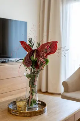 a glass vase with red flowers on a table at Vincent Sunlight Stay - Near Clinic, Arena and Stadium in Kaunas