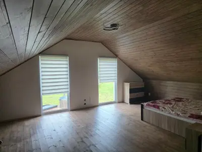 an attic room with a bed and two windows at Friend's homestead