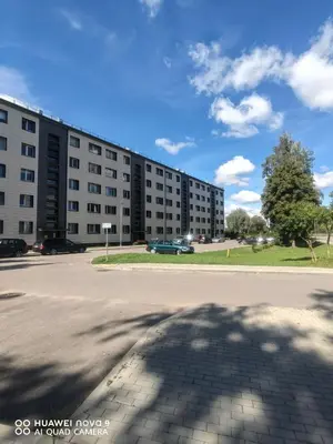 a large building with a parking lot in front of it at Next door airport apartment in Karmėlava