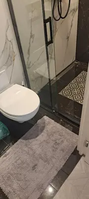 a bathroom with a toilet and a rug next to a shower at Next door airport apartment in Karmėlava