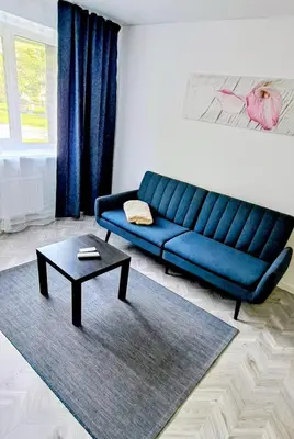 a blue couch in a living room with a coffee table at Next door airport apartment in Karmėlava