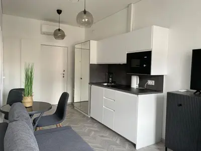 a kitchen with white cabinets and a table in a room at Suite in the heart of the city in Panevėžys