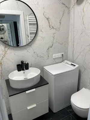 a white bathroom with a sink and a mirror at Suite in the heart of the city in Panevėžys