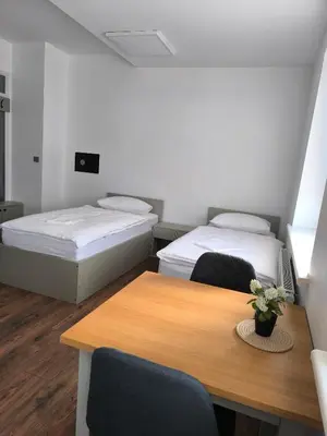 a room with two beds and a wooden table at Apartamentai1 in Utena