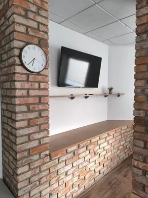 a brick wall with a clock and a tv on a wall at Apartamentai1 in Utena