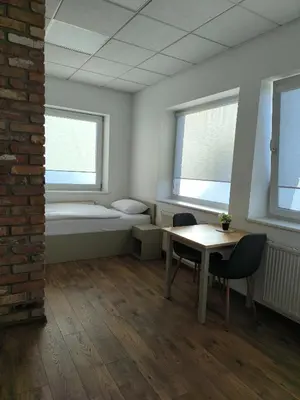 a room with a table and chairs and two windows at Apartamentai1 in Utena