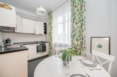a kitchen with white cabinets and a table with a plant at Vokieciu st Apt with Balcony I In the Center of it All I cohost in Vilnius