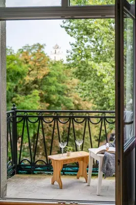 a table with two wine glasses on a balcony at Vokieciu st Apt with Balcony I In the Center of it All I cohost in Vilnius