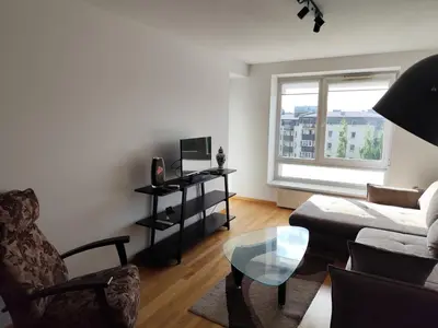 a living room with a couch and a glass table at Jaukūs apartamentai in Vilnius