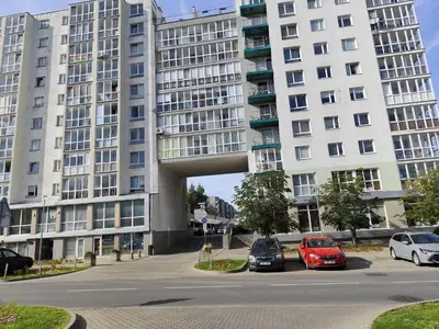a large apartment building with cars parked in a parking lot at Jaukūs apartamentai in Vilnius
