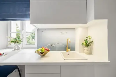 a white kitchen with a bowl of fruit on a sink at Blue Old Town apartment in Vilnius