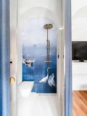 a bathroom with a mural of birds on the wall at Blue Old Town apartment in Vilnius