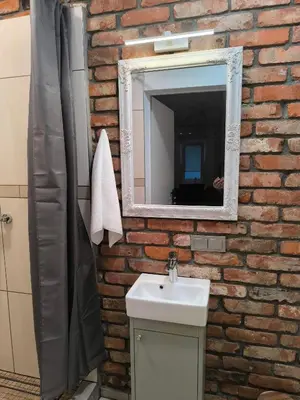 a brick bathroom with a sink and a mirror at Studio 2 in Utena