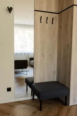 a room with a mirror and a bench and a chair at Alėjos apartamentai in Šiauliai