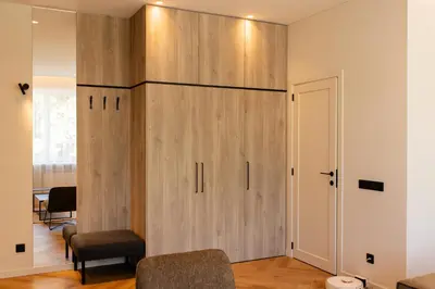 a large wooden cabinet in a room with a table at Alėjos apartamentai in Šiauliai
