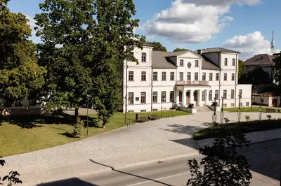a large white house with a road in front of it at Alėjos apartamentai in Šiauliai