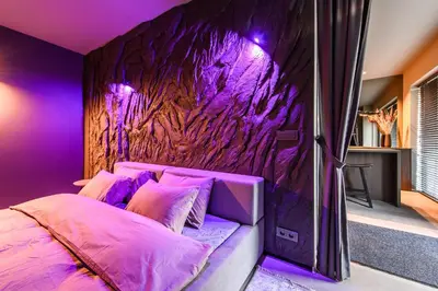 a bedroom with a purple wall and a bed with pillows at Jacuzzi Cinema Japandi 2 in Kaunas