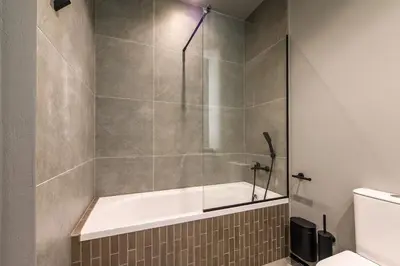 a bathroom with a shower with a tub and a toilet at Jacuzzi Cinema Wabi Sabi 3 in Kaunas