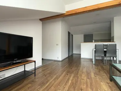 a living room with a flat screen tv and a table with chairs at newTown 1 in Kaunas