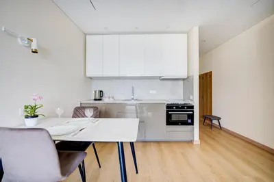 a white kitchen with a table and chairs at Pradoli apartament in Vilnius