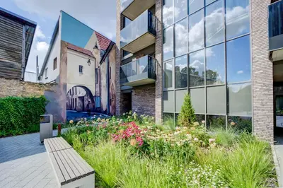 a garden in front of a building with a bench at Pradoli apartament in Vilnius