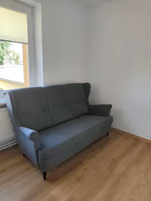 a blue couch in a room with a window at CityPark Stay in Šiauliai