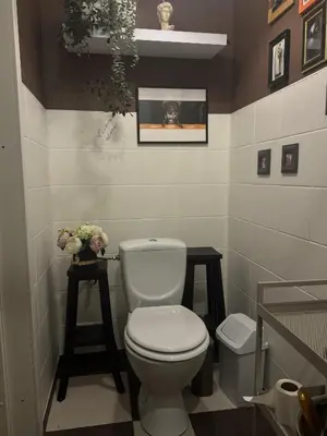 a bathroom with a white toilet and two stools at Saga studio in the center of Pasvalys in Pasvalys