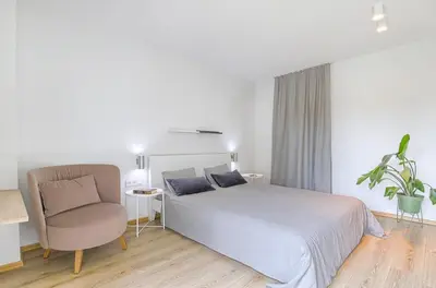 a white bedroom with a bed and a chair at Spacious 2 Bedroom Apartment in Central Vilnius in Vilnius
