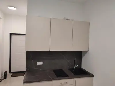 a kitchen with white cabinets and a black counter top at CenterStudioFlat in Vilnius