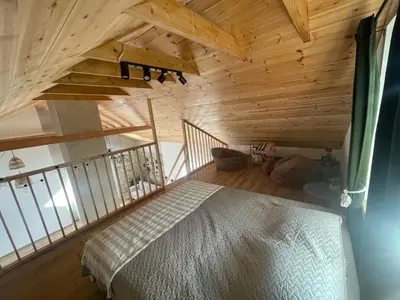 a bedroom with a bed in a room with wooden ceilings at LilHouse loftas Šiauliuose in Šiauliai