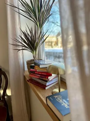 a pile of books sitting on a table next to a window at Jaukus Aleksoto butas Kaune su atskiru įėjimu, šalia Senamiesčio in Kaunas
