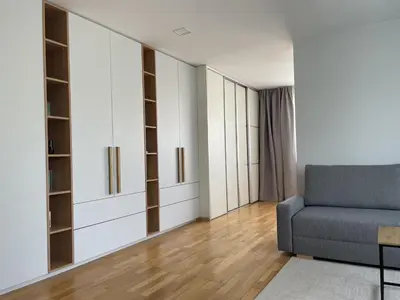 a living room with a blue couch and white cabinets at Šiaulių centre modernus butas 1-4 žmonėms in Šiauliai