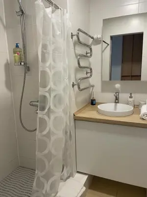 a bathroom with a shower curtain next to a sink at Šiaulių centre modernus butas 1-4 žmonėms in Šiauliai